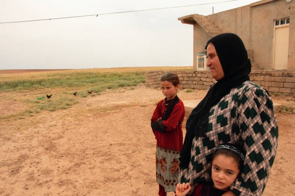 Leyla, mère de famille du hameau de Hassan Jelad, regarde les champs déminés devant sa maison autrefois occupée par le groupe État islamique.